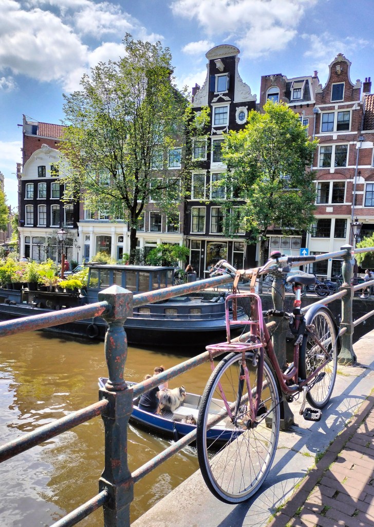View from a bridge across a canal in Amsterdam, with typical Dutch houses along the sides.