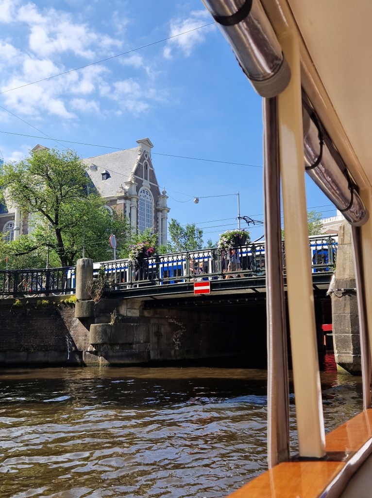 A bridge across a canal in Amsterdam. A tram and cyclists moving across the city
