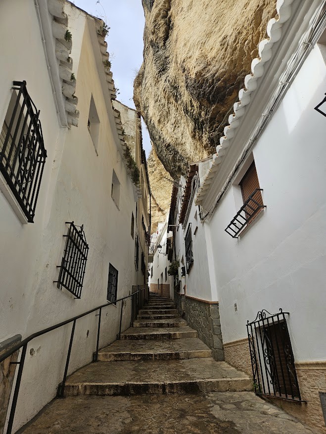 Picturesque Calle Herrería, a street in Setenil de la Bodegas lined with white houses and stone stairways built directly into the rock face.